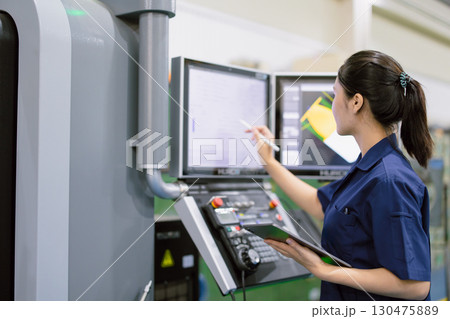 young technician engineer worker with CNC lathe metal machine in modern steel industry factory 130475889