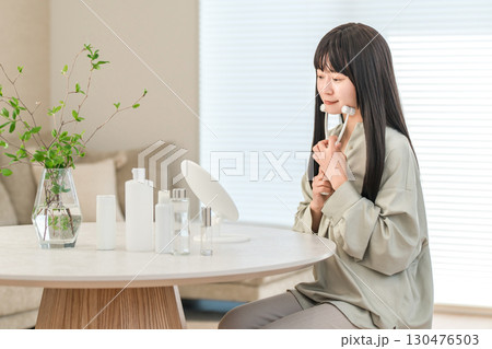自宅のリビングで美顔ローラーを使ってマッサージするアジア人女性 130476503