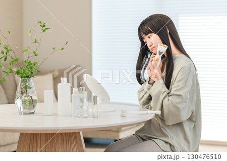 美顔器を使ってホームエステ・リフトアップ・マッサージする笑顔のアジア人女性（悩み,悩む,困る） 130476510