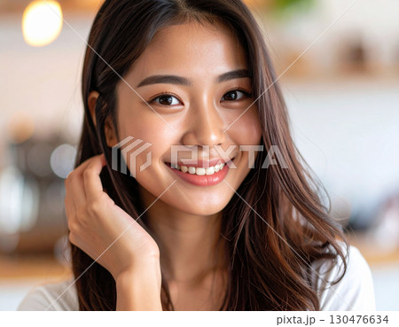 髪をかき上げる若い女性/Young woman combing her hair	 130476634