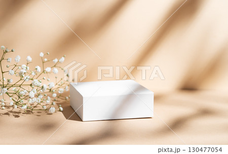 White square box on a beige background with gypsophila flowers and soft shadows. 130477054