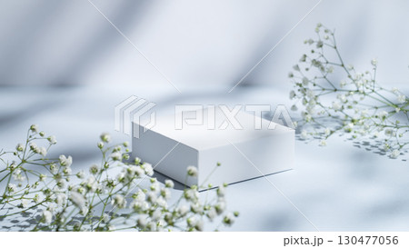 White square box on a blue background with gypsophila flowers and shadows. White square box on a blue background with gypsophila flowers and shadows. 130477056