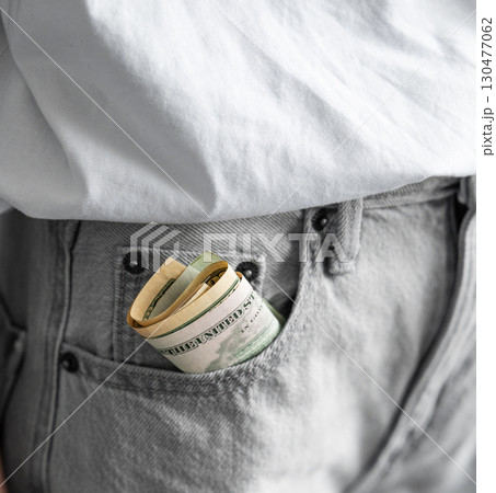 Rolled up US dollar bills sticking out of front pocket of jeans on casual clothing background Rolled up US dollar bills sticking out of front pocket of jeans on casual clothing background 130477062