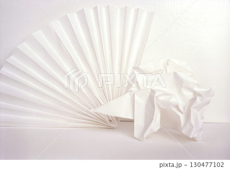 Artwork featuring white paper fan and crumpled paper on blank background showcasing texture and simplicity 130477102