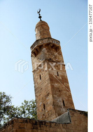 Historic minaret stands tall against a clear blue sky in a serene landscape Historic minaret stands tall against a clear blue sky in a serene landscape 130477107