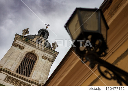 Historic church tower viewed from below with ornate lantern in foreground on a cloudy day Historic church tower viewed from below with ornate lantern in foreground on a cloudy day 130477162