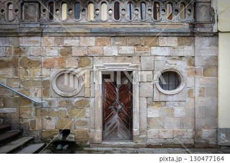 Old architectural structure featuring a wooden door and stone wall in a historical urban setting 130477164