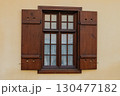 Wooden window with shutters and grid design on a beige wall in a historic building 130477182