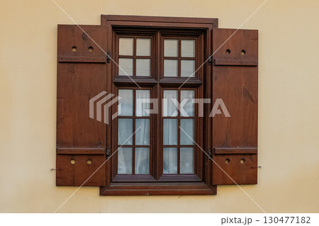Wooden window with shutters and grid design on a beige wall in a historic building Wooden window with shutters and grid design on a beige wall in a historic building 130477182