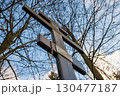 Cross surrounded by bare trees under a clear sky during sunset near a historical site 130477187