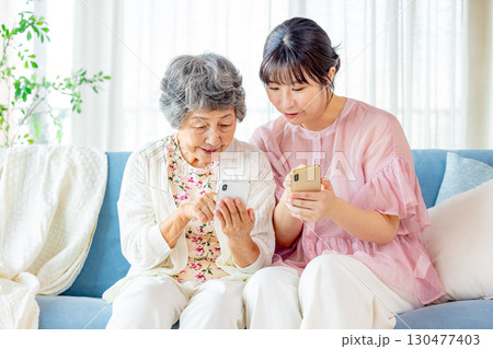 スマホで孫と遊ぶシニア女性 130477403