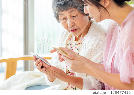 シニア女性にスマホの使い方を教える女性 130477410