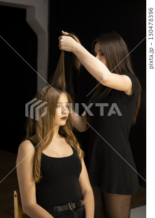 Hairdresser styling long hair of young woman with curls in beauty studio Hairdresser styling long hair of young woman with curls in beauty studio 130478396