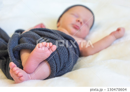 Newborn baby peacefully sleeping on soft blanket wrapped in shawl at home in natural light 130478604