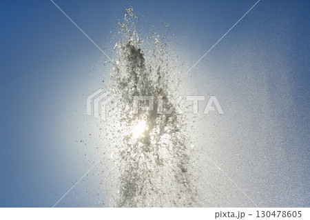 Water fountain sprays sunlight into a clear blue sky during a bright afternoon Water fountain sprays sunlight into a clear blue sky during a bright afternoon 130478605