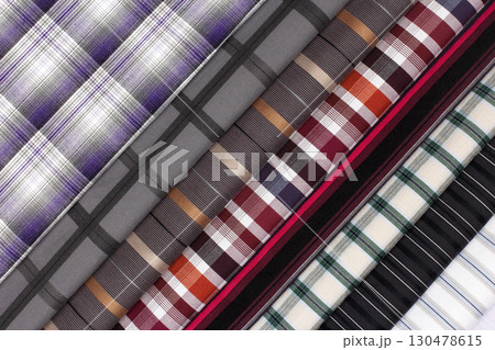 Patterns of woven fabric showcase colorful plaid designs in a textile display 130478615