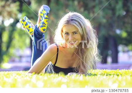 Young woman relaxing on grass in a park during a sunny afternoon 130478785
