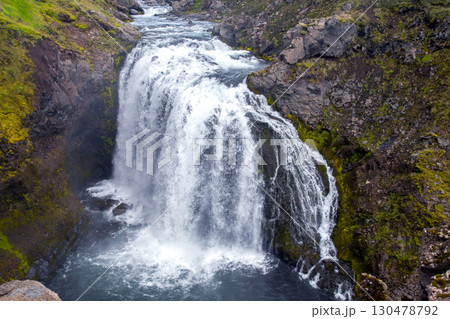 Majestic waterfall cascading into river surrounded by lush green moss in Iceland Majestic waterfall cascading into river surrounded by lush green moss in Iceland 130478792