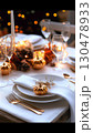 Metallic pumpkins, pine cones, and glowing string lights adorning rustic Thanksgiving tablescape with white dinnerware, golden utensils, and sparkling champagne glasses 130478933