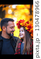 Cheerful parent and child bonding, wearing handcrafted maple leaf crown, sharing warm smile amid golden autumn park landscape with vibrant seasonal colors 130478966