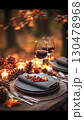 Rustic autumn table arrangement with wine glasses, glowing candles, scattered pine cones, crimson berries staging intimate dining experience amid natural woodland ambiance 130478968
