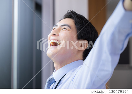 窓際でストレッチする休憩する爽やかなビジネスマン男性のクローズアップ　スッキリした表情 130479194