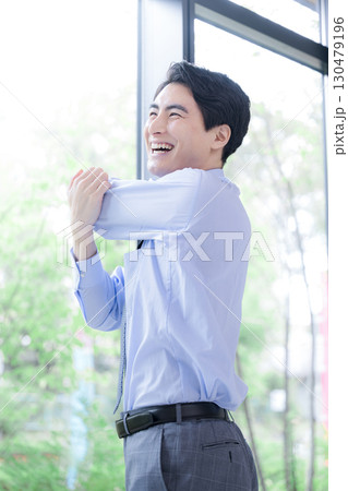 窓際でストレッチする休憩するビジネスマン 窓際でストレッチする休憩するビジネスマン 130479196