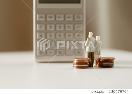 計算機の前に立つミニチュアの老夫婦と硬貨 年金 老後のお金イメージ  130479764