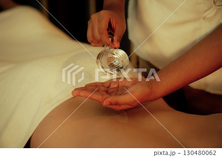 Closeup masseuse prepare oil massage procedure for customer at spa. Quiescent Closeup masseuse prepare oil massage procedure for customer at spa. Quiescent 130480062