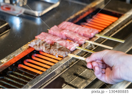 Hand barbecuing the delicious hida beef with high marbling on skewers at street market. 130480885