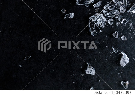 Shattered glass fragments on dark surface with high contrast and texture 130482392