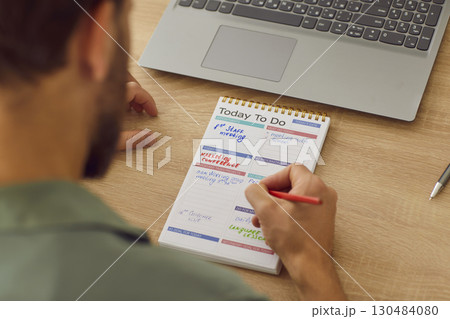 Top view of businessman planning tasks and to do list in his notepad sitting at home or at office Top view of businessman planning tasks and to do list in his notepad sitting at home or at office 130484080