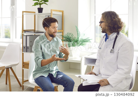 Bearded young male patient visiting a doctor in clinic for medical examination. Bearded young male patient visiting a doctor in clinic for medical examination. 130484092