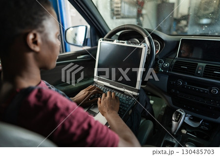 Car mechanic running diagnostics on a vehicle using a laptop Car mechanic running diagnostics on a vehicle using a laptop 130485703