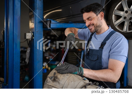 Mechanic repairing a car engine in a workshop 130485708
