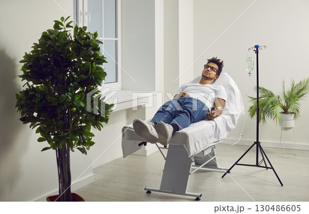 Male patient lying in hospital bed with iv drip attached to his hand Male patient lying in hospital bed with iv drip attached to his hand 130486605