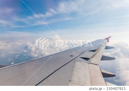 View from the airplane window at a beautiful cloudy sky and the airplane wing View from the airplane window at a beautiful cloudy sky and the airplane wing 130487921