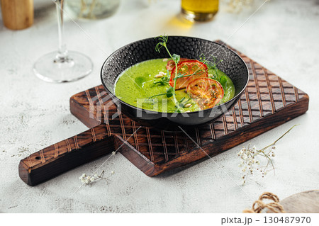 Green vegetable soup with tomato chips in bowl 130487970