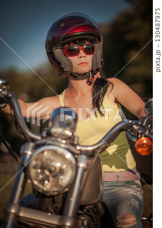 Biker woman sitting by her motorcycle... 130487975