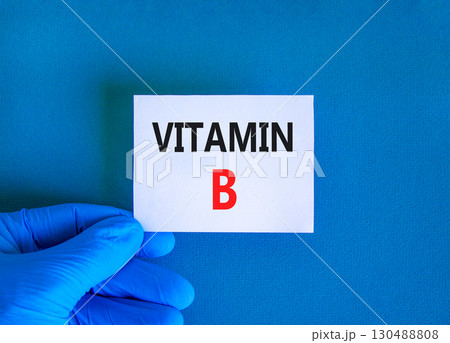 Vitamin B symbol. Concept words Vitamin B on beautiful white card. Doctor's hand in blue medical glove. Beautiful blue background. Medical healthy lifestyle Vitamin B concept. Vitamin B symbol. Concept words Vitamin B on beautiful white card. Doctor's hand in blue medical glove. Beautiful blue background. Medical healthy lifestyle Vitamin B concept. 130488808