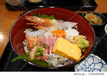 日本食、生の魚の刺身をご飯にのせた海鮮丼という料理 130489560