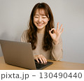 パソコンで仕事をする女性の笑顔とOKサイン 130490440