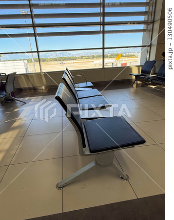 Empty waiting area in airport terminal with view of runway. Travel, observation, and waiting moments in passenger transportation spaces. Empty waiting area in airport terminal with view of runway. Travel, observation, and waiting moments in passenger transportation spaces. 130490506