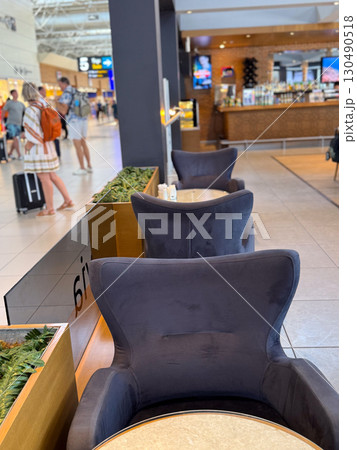 Comfortable lounge chairs and tables in airport cafe area. Leisure, travel and social interaction in public hospitality spaces. Comfortable lounge chairs and tables in airport cafe area. Leisure, travel and social interaction in public hospitality spaces. 130490518
