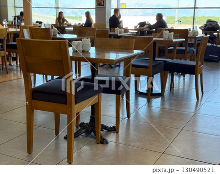Wooden tables and chairs in a bright cafe interior. Socialization, leisure and human connection in everyday hospitality spaces. 130490521