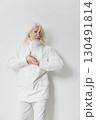elderly man wearing a stylish white jacket standing against a plain white background, showcasing modern fashion and confidence with a subtle expressive gesture 130491814