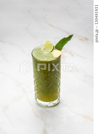 Green detox smoothie with lime and mint in a glass on marble background Green detox smoothie with lime and mint in a glass on marble background 130491931
