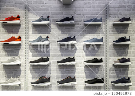 Shop display of unbranded modern new stylish sneakers running shoes for men on brick wall background texture. 130491978