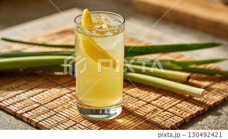 Bright ginger lemongrass cocktail with citrus spiral served in tall clear glass 130492421