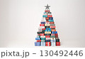 Many wrapped gift boxes forming a christmas tree shape stand in front of a white background, topped with a decorative star, creating a festive holiday scene 130492446